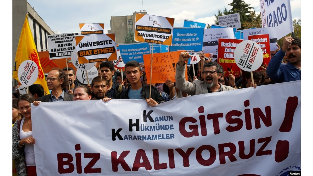 FILE - Demonstrators hold signs in front of the High Education Board as they protest the suspension of academics from universities after a post-coup emergency decree, in Ankara, Turkey, Sept. 22, 2016.