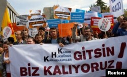 FILE - Demonstrators hold signs in front of the High Education Board as they protest the suspension of academics from universities after a post-coup emergency decree, in Ankara, Turkey, Sept. 22, 2016.