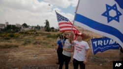 FILE - Israelis hold American and Israeli flags with the new U.S. Embassy in the background in Jerusalem, May 14, 2018. Seventy years after Israel's founding, images of victory and violence showcased the contradictions that bedevil the Jewish state.