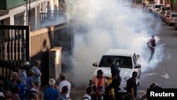 Personas reaccionan a bombas lacrimógenas durante una encuentro de simpatizantes del líder de la oposición venezolana Juan Guaidó en Caracas. Photo: Reuters