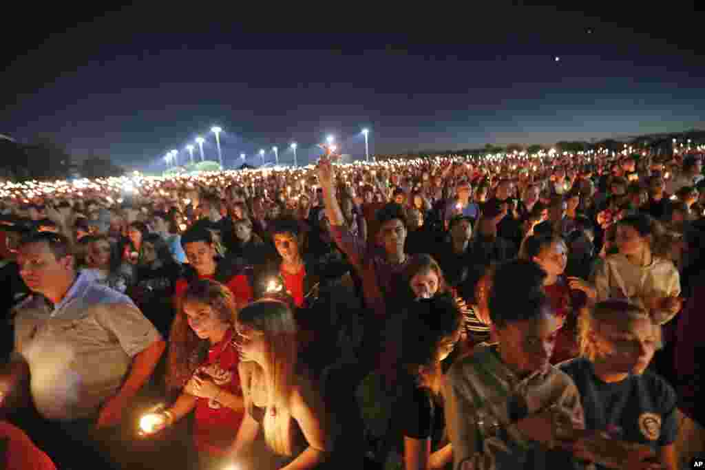 People hoist up their candles during a vigil for the victims of the Wednesday shooting at Marjory Stoneman Douglas High School, in Parkland, Fla., Feb. 15, 2018.