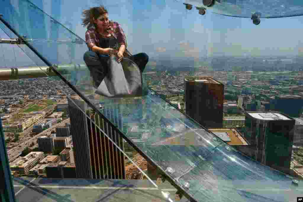 A member of the media rides down a glass slide during a preview at the U.S. Bank Tower building in downtown Los Angeles, June 23, 2016. Starting this weekend, thrill-seekers can begin taking the Skyslide, a 1,000-foot-high slide, perched on the outside of the tallest skyscraper west of the Mississippi.&nbsp;