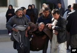 A distraught man is carried away following a suicide attack in Kabul, Afghanistan, Dec. 28, 2017. Authorities say attackers stormed the Shiite Muslim cultural center in the Afghan capital Kabul, setting off multiple bombs and killing dozens.