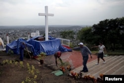 Para pekerja membersihkan Loma de la Cruz, sehari sebelum kunjungan Paus Fransiskus ke Holguin di Kuba, 20 September 2015.