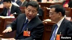 China's Communist Party Chief Xi Jinping speaks to Vice Premier Li Keqiang, presidium of the first session of the 12th National People's Congress, Beijing, March 4, 2013.