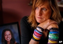 FILE - Judi Richardson, a citizen sponsor of a ballot initiative to require background checks for gun buyers, wears wrist bands bearing the names and places of victims of gun violence, at her home in South Portland, Maine.