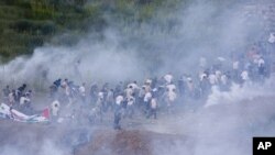 Pro Palestinians protesters run from tear gas fired by Israeli troops along the border between Israel and Syria near the village of Majdal Shams in the Golan Heights, Sunday, June 5, 2011