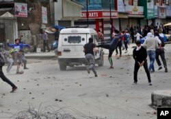 Kashmiri students and other protesters throw stones at an Indian police vehicle as they clash with police in Srinagar, Indian controlled Kashmir, April 24, 2017.