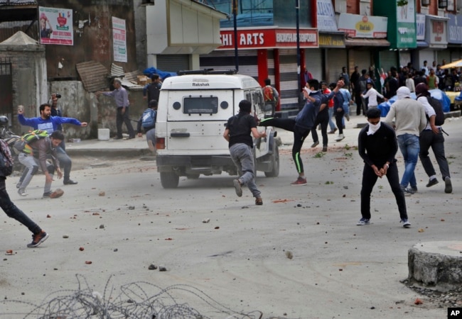 Kashmiri students and other protesters throw stones at an Indian police vehicle as they clash with police in Srinagar, Indian controlled Kashmir, April 24, 2017.