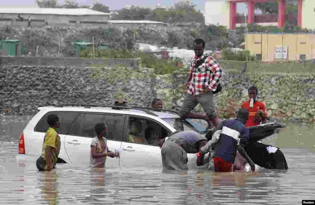 Residents attempt to push a car stalled in flood water following heavy rain in Somalia&#39;s capital Mogadishu.