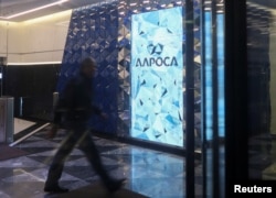 FILE - A man walks past the logo of Russia's diamond producer Alrosa at the entrance of the company's headquarters in Moscow, Russia, Jan. 26, 2018.