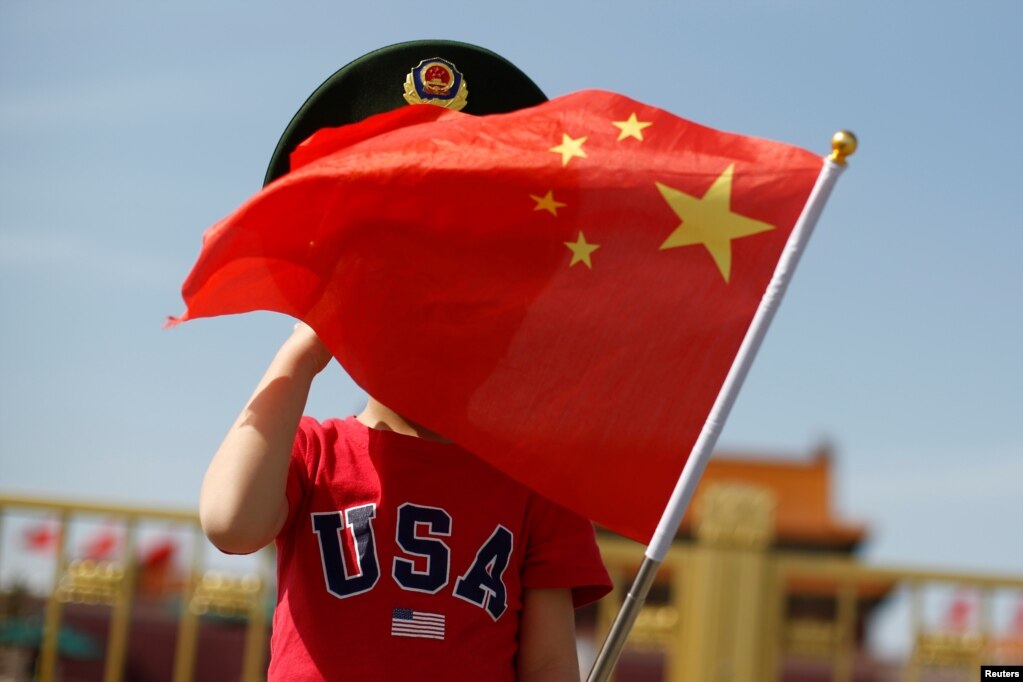 一名站在北京天安门广场的小男孩身穿美国T恤手拿中国国旗。（2019年5月7日）(photo:VOA)
