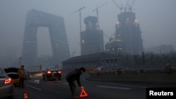 Công nhân đặt biển báo tại hiện trường một vụ tai nạn xe giữa bầu không khí đặc khói mù ở Bắc Kinh sau khi thành phố này đưa ra báo động đỏ lần thứ nhất hôm 8/12/2015.