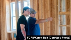 Student Shane Bhatti and teacher Ron Meinert discuss the home-building project.