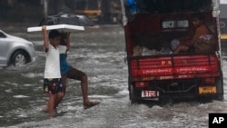 Indian boys navigate their way through a waterlogged street in Mumbai, India, Sept. 20, 2017.