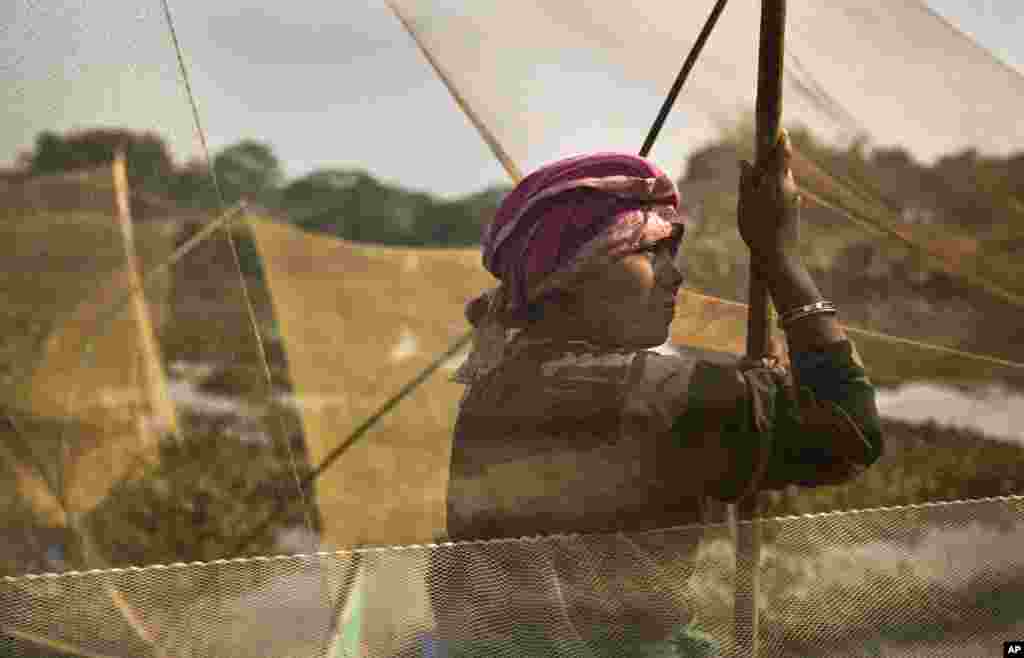 A Karbi tribal woman waits with her fishing net to participate in community fishing as part of Bhogali Bihu celebrations in Panbari village, some 50 kilometers (31 miles) east of Gauhati, India. &quot;Bhogali Bihu&quot; marks the end of the harvest season in the northeastern state of Assam.