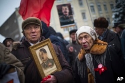 FILE - A man holds a portrait of Soviet dictator Josef Stalin during a demonstration marking the 99th anniversary of the 1917 Bolshevik Revolution in Moscow, Russia, Nov. 7, 2016. Unlike the past, Nov. 7 is no longer a public holiday in Russia.