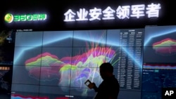 FILE - In this Aug. 16, 2016, photo, a worker is silhouetted against a computer display showing a live visualization of online phishing and fraudulent phone calls across China during the 4th China Internet Security Conference (ISC) in Beijing.
