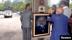 Officials move a portrait of Meles Zenawi shortly after the announcement of his death in Addis Ababa August 21, 2012. 