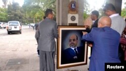 Officials move a portrait of Meles Zenawi shortly after the announcement of his death in Addis Ababa August 21, 2012. 