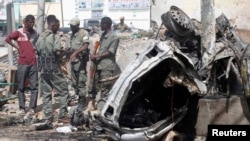 Des agents de sécurité se tiennent sur les lieux de l'explosion d'une voiture piégée le long de la jonction de la route du «Kilomètre 4 », au sud de la capitale Mogadiscio, en Somalie, le 5 mai 2013.