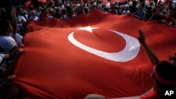 Protestors wave a large Turkish flag during an anti coup rally in Taksim square in Istanbul, July 25, 2016. 