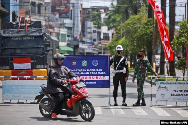 Sejumlah tentara menjaga penyekatan PPKM darurat untuk meredam penyebaran pandemi COVID-19 di Medan, Sumatera Utara, Kamis, 15 Juli 2021. (Foto: Binsar Bakkara/AP)