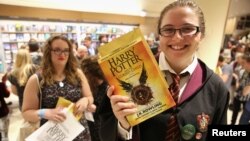 A young woman holds copies of the book from the play of "Harry Potter and the Cursed Child" parts One and Two at a bookstore in London, July 31, 2016.