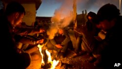 Afghan refugees gather around a fire to warm themselves in the early hours while waiting to get on board a ferry traveling to Athens, at the port of Mitylene on the northeast Greek island of Lesbos, Oct. 9, 2015.