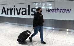 Seorang penumpang mengenakan masker tiba di bandara Heathrow, London barat, Inggris, di tengah pandemi Covid-19,10 Juli 2020