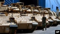 A Lebanese army soldier walks near military vehicles that were unloaded from a ship at Beirut's port in Lebanon, Aug. 14, 2017.