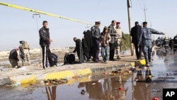 Security forces and people inspect the scene of a bomb attack on Shi'ite pilgrims, near the southern port city of Basra, Iraq's second-largest city, 550 kilometers southeast of Baghdad, Saturday, Jan. 14, 2012.