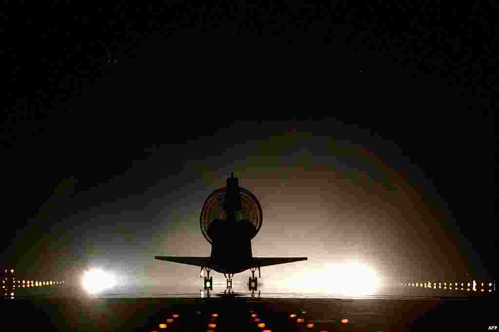 With its drag chute fully deployed, space shuttle Discovery lands on Kennedy's brightly lighted Shuttle Landing Facility runway 15, completing the 9-day mission, June 6, 1999. (NASA)