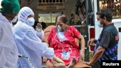 ကိုဗစ်ကူူးစက်ခံရသူတဦးကို ကျန်းမာရေးဝန်ထမ်းများ ဆေးရုံသို့ ပို့ဆောင်ပေးနေတဲ့ မြင်ကွင်းကို အိန္ဒိယနိုင်ငံ Mumbai မြို့မှာ တွေ့ရ။ (မေ ၄၊ ၂၀၂၁)