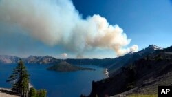 This photo provided by Inciweb.gov, shows smoke from Bybee Creek Wildfire drifting over Crater Lake, Oregon., July 30, 2016. 