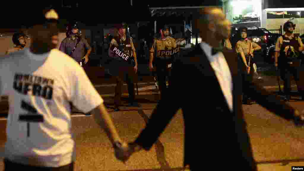 Civilian peacekeepers join hands to separate demonstrators protesting against the shooting of Michael Brown away from the police in Ferguson, Missouri, Aug. 19, 2014.