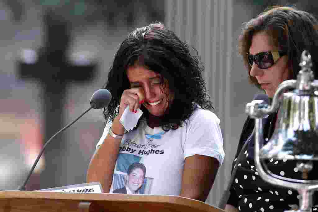 A woman wipes her eyes after reading the name of her brother, Bobby Hughes, as friends and relatives of the victims of the 9/11 terrorist attacks gather at the National September 11 Memorial at the World Trade Center site, Sept. 11, 2013.