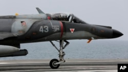 FILE - A French military plane lands on the French navy aircraft carrier Charles de Gaulle in the Persian Gulf, March 18, 2015. France has fired its first airstrikes in Syria as it expands military operations against Islamic State extremists, President Francois Hollande's office announced, Sept. 27, 2015.