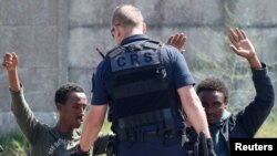 Un policier fouille des migrants à genoux près de Calais, France, 1er juin 2017.