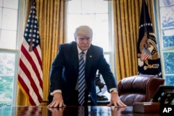 President Donald Trump poses for a portrait in the Oval Office of the White House in Washington, April 21, 2017.