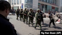 Heavily armed Chinese paramilitary police men march past the site of the late April explosion outside the Urumqi South Railway Station in Urumqi in northwest China's Xinjiang Uygur Autonomous Region. China blames Islamic extremists for this and other recent deadly attacks.