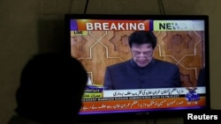 A man looks at a television screen displaying cricketer-turned-politician Imran Khan being sworn in as prime minister of Pakistan, in Karachi, Pakistan, Aug. 18, 2018.