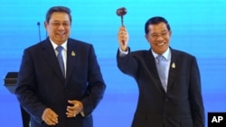 Cambodian Prime Minister Hun Sen (R) waves a gavel after taking over the ASEAN chairmanship from Indonesian President Susilo Bambang Yudhoyono during the handover ceremony at the closing session of ASEAN Summit and Related Summits in Nusa Dua, Bali Novemb