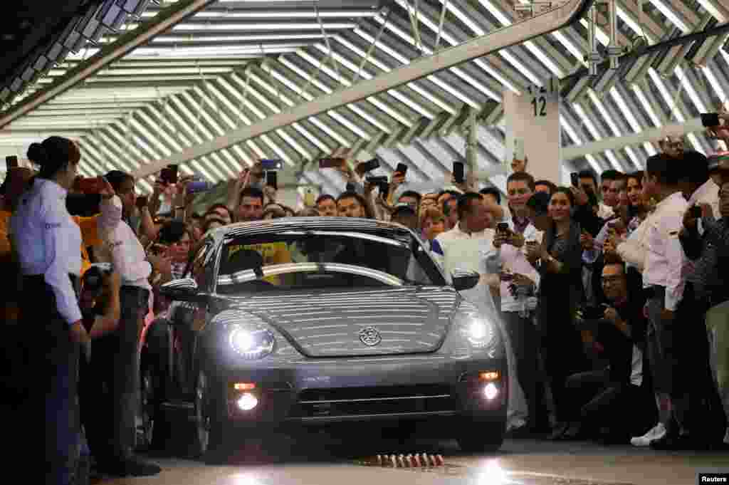 Employees take pictures of a Volkswagen Beetle car during a ceremony marking the end of production of VW Beetle cars, at company's plant in Puebla, Mexico, July 10, 2019. The last Beetle is not for sale, but instead will go to a museum.