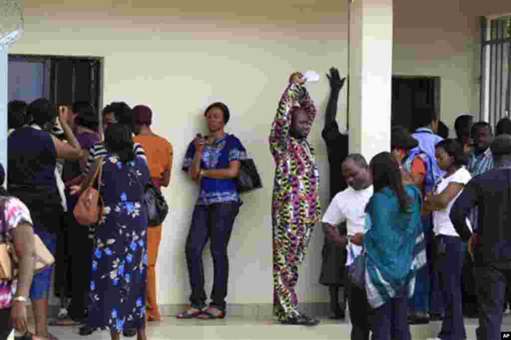 United Nations workers wait outside U.N. headquarters in hopes of recovering belongings from their offices, one day after a suicide bomber crashed through an exit gate and detonated a car full of explosives in the building's reception area, in Abuja, Nige