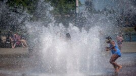 While Portland reached a record temperature of over 110 degrees Sunday, June 27, 2021 people gathered at Salmon Street Springs water fountain in Portland to cool off. (Mark Graves/The Oregonian via AP)