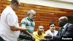 FILE - Baktash Akasha, from left, Gulam Hussein, Ibrahim Akasha and Vijaygiri Goswami are briefed by their lawyer Cliff Ombeta at Mombasa Law Courts during a court appearance on drug-related charges in Mombasa, Kenya, Feb. 17, 2015.