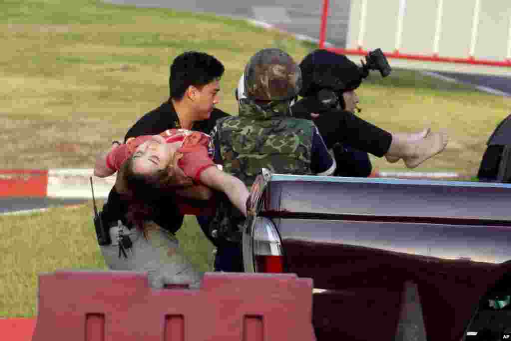 Armed commando soldiers carry a woman who fainted, out of Terminal 21 Korat mall where a mass shooting took place in Nakhon Ratchasima, Thailand. A gunman described as a soldier angry over a financial dispute killed a few people and then went on a far bloodier rampage, shooting as he drove to the busy mall where shoppers fled in terror.