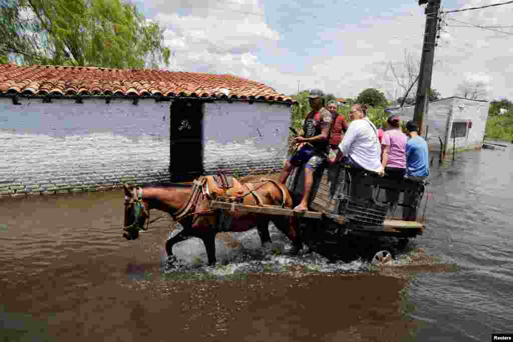People ride on a horse carriage through a flooded street after heavy rains caused the Paraguay River to overflow, in Asuncion, Paraguay, Jan. 22, 2018.