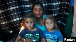 Maria Lila Meza, a 39-year-old migrant woman from Honduras, part of a caravan of thousands from Central America trying to reach the U.S., sits with her five-year-old twin daughters Cheili Nalleli Mejia Meza and Saira Nalleli Mejia Meza inside their tent in Tijuana, Nov. 26, 2018.